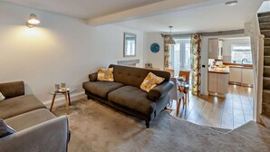 Ein Wohnzimmer mit einer Couch, einem kleinen Tisch und einer Treppe, die zur Küche führt.