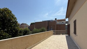 Une terrasse sur le toit, dotée d’un sol carrelé, d’un petit muret et d’une grille en métal.