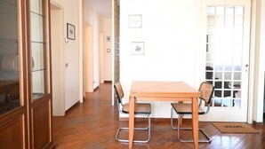 Une pièce comprenant une table à manger en bois, deux chaises, un buffet et une porte dotée d’un panneau en verre.