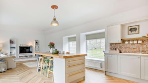 Een moderne keuken met een centraal eiland, witte kastjes en een visgraatvloer.
