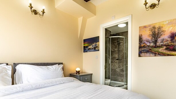 A bedroom with a bed, a nightstand, a painting, and a shower. - 4 Bed in Bala (oc-75288) (Llandderfel)