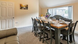 A dining room with a wooden table set for six, surrounded by chairs, a chandelier, and a painting on the wall. - 4 Bed in Bala (oc-75288) (Llandderfel)