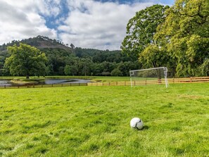 A soccer field with a goalpost and a ball, surrounded by a fence and trees. - 4 Bed in Bala (oc-75288) (Llandderfel)