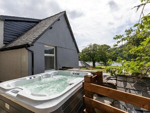 Boblebad i en baghave med et hus, en træterrasse og udsigt til søen.