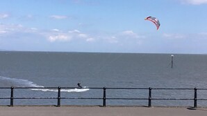 A coastal view with a person windsurfing, a railing, and a distant buoy.