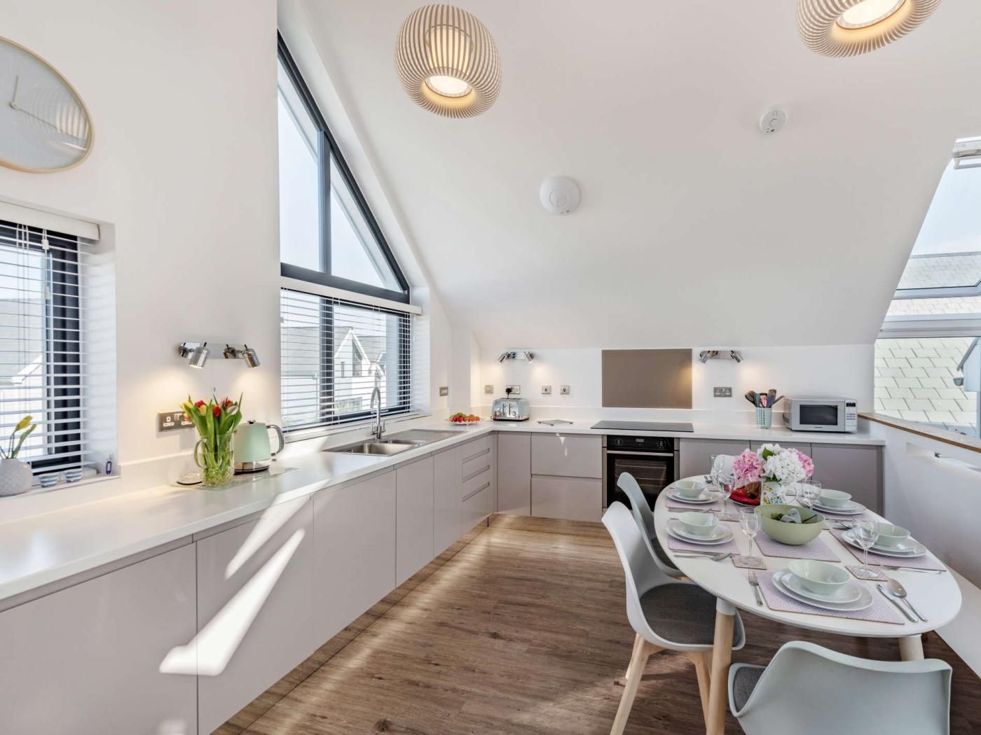 A modern kitchen with a dining area, large windows, and a sloped ceiling.