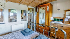 Interior de madeira com cama, cômoda e espelho.