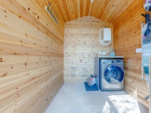 A compact, wooden interior with a washing machine and a drying rack.