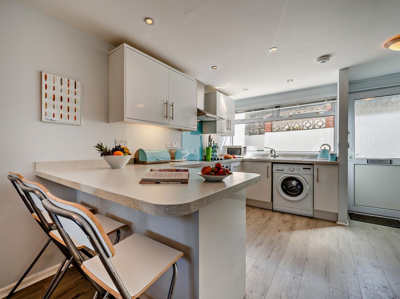 A modern kitchen with a central island, built-in appliances, and a view to the outside.