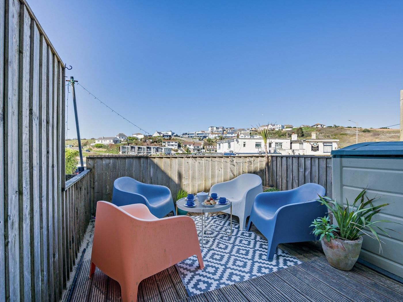 Un balcon avec des chaises bleues, une petite table et une plante en pot.