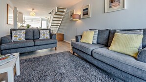A modern living room with a grey sofa set, a patterned rug, and a staircase leading to an upper level. - 2 Bed in Newquay (oc-75578) (Newquay)