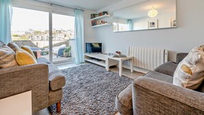 A modern living room with a sofa, a coffee table, a TV, and a bookshelf. - 2 Bed in Newquay (oc-75578) (Newquay)
