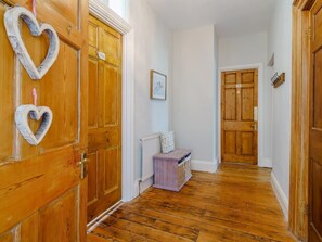 Ein Holzboden-Flur mit einer Sitzbank, einem Heizkörper und einer Tür mit Herz-Dekoration.