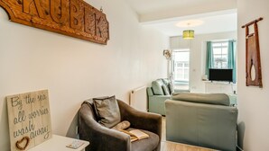 Uma sala de estar aconchegante com um sofá, uma poltrona e uma placa de madeira com a palavra 'KUBIK' na parede.