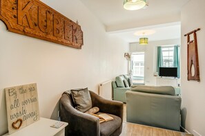 A cozy living room with a sofa, a chair, and a wooden sign with the word 'KUBIK' on the wall. - 2 Bed in Brixham (oc-75549) (Brixham)