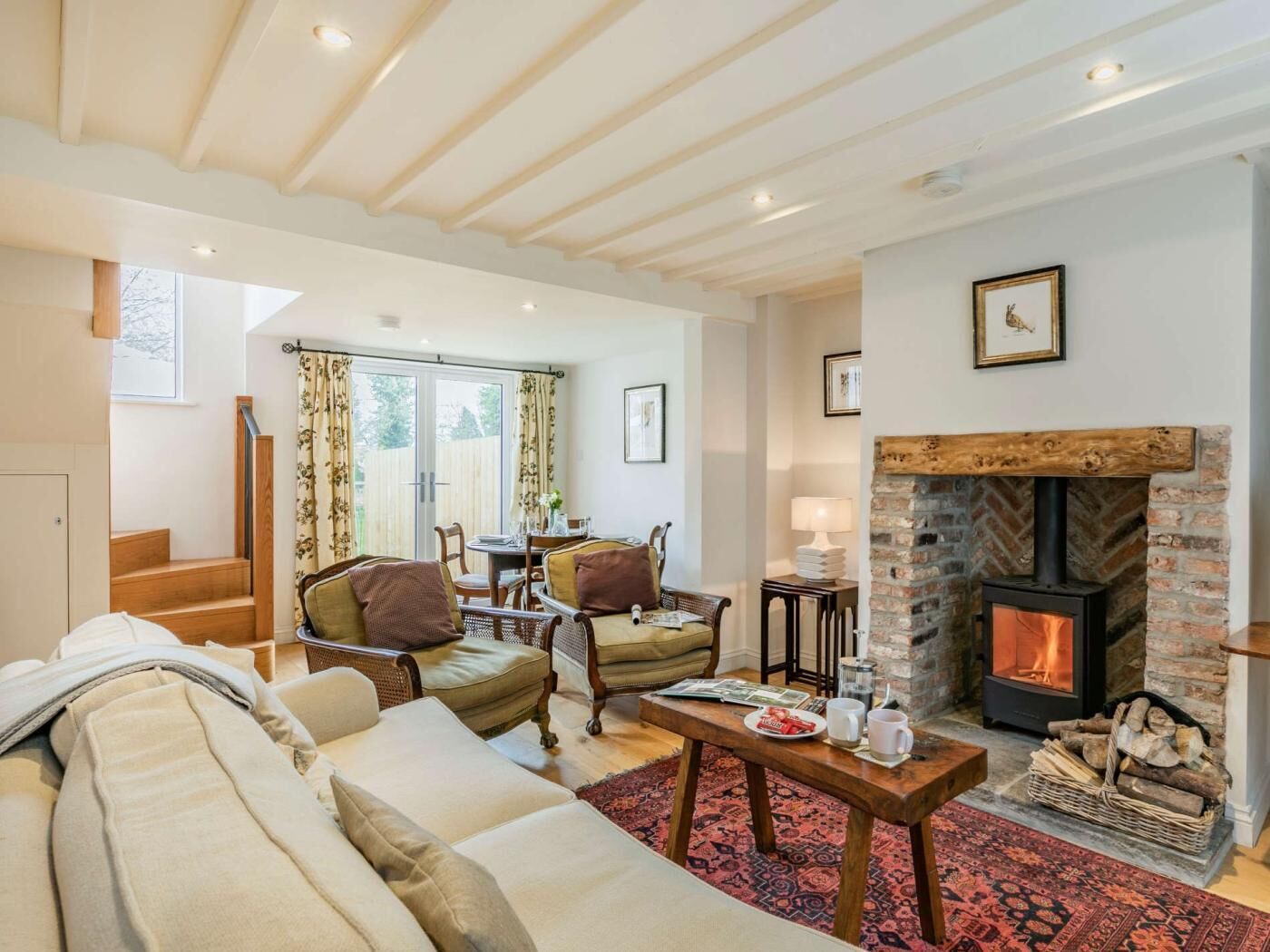 A cozy living room with a fireplace, a dining area, and a staircase leading to another level.