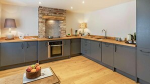 Eine moderne Küche mit Backsteinwand, Holz Arbeitsplatte und eingebauten Geräten.