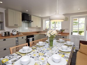 A modern kitchen with a dining area set for a meal. - 4 Bed in Dorchester (oc-75851) (Litton Cheney)