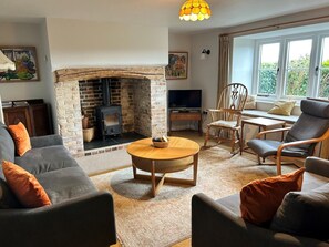 A cozy living room with a fireplace, comfortable seating, a television, and a large window. - 4 Bed in Dorchester (oc-75851) (Litton Cheney)