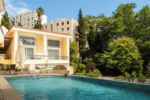 A hotel with a swimming pool, outdoor seating, and a view of surrounding greenery. - Gold 3 Apartment (Cannes)