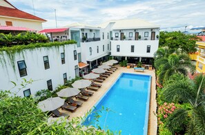 Un hotel con piscina, tumbonas y una zona de estar exterior cubierta.