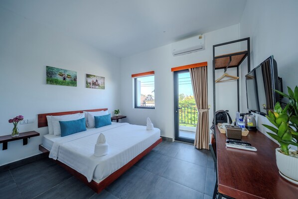 A hotel room with a large bed, a desk with a mirror, and a balcony with a view. - Onederz Kampot (Kampot)
