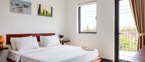 Habitación de hotel con una cama, una mesita de noche, un ventanal y dos cuadros colgados en la pared.