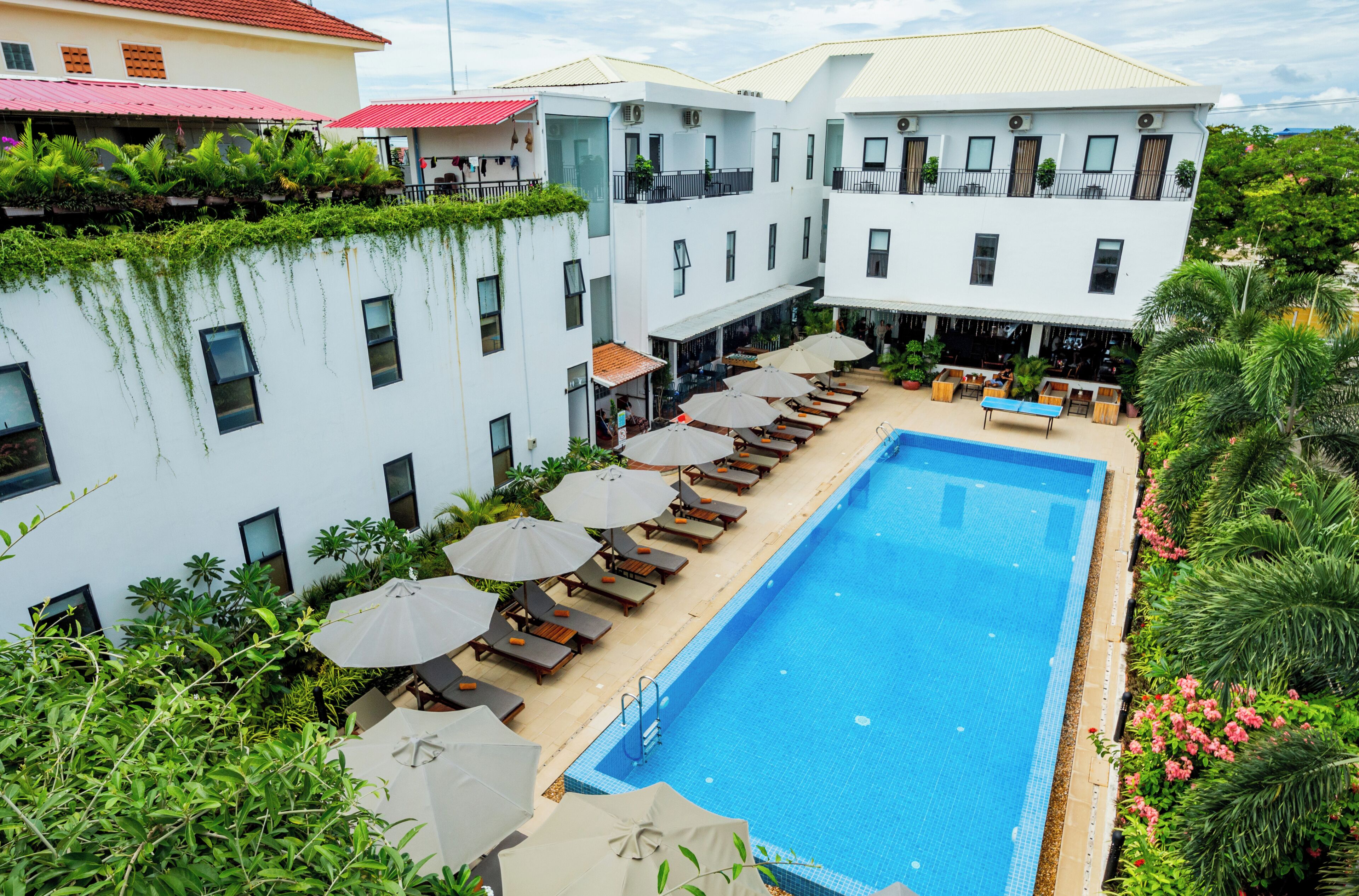 A hotel with a swimming pool, sun loungers, and umbrellas.