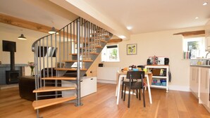 Un intérieur moderne avec un escalier en colimaçon, un plancher en bois, un coin cuisine et un espace repas.