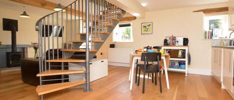A modern interior with a spiral staircase, wooden flooring, a kitchen area, and a dining space.