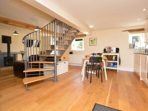 Ein modernes Interieur mit einer Wendeltreppe, Holzboden, einer Küchenzeile und einem Essbereich.