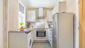 Een kleine keuken met een wasmachine, oven en koelkast.