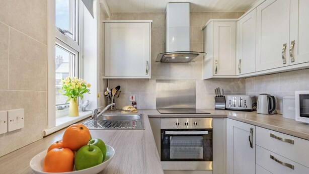 Een moderne keuken met witte kasten, een roestvrijstalen oven, een magnetron en een spoelbak.