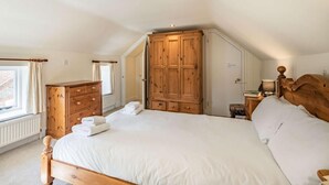 Une chambre avec un grand lit, une armoire en bois et une fenêtre avec des rideaux.
