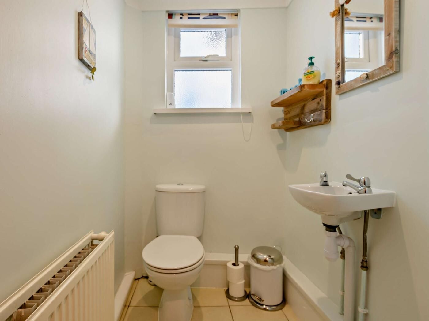 Een kleine, schone badkamer met toilet, wastafel en raam.