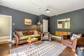 Ein Wohnzimmer mit einem braunen Ledersofa, einem kleinen runden Tisch und einem gemusterten Teppich.