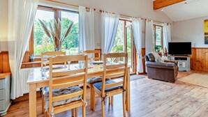 A spacious living area with a dining table, chairs, a sofa, and a television.