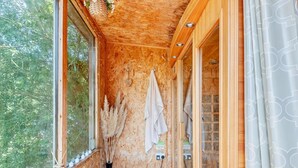 A narrow hallway with wooden walls, a window with candles, a towel hanging, and a door leading to a bathroom.