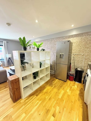 Een moderne keuken met een ingebouwde witte schapunit, een roestvrijstalen koelkast en een houten kast.
