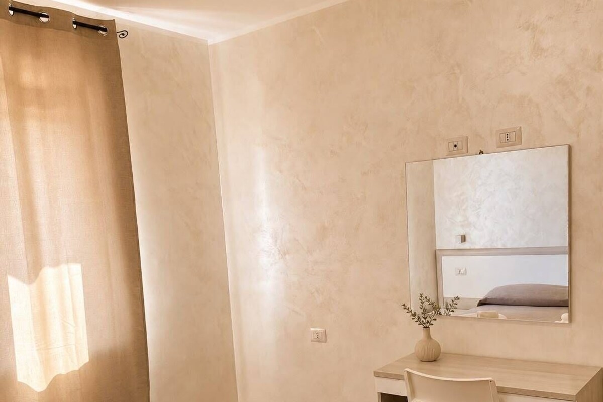 Une chambre d’hôtel comprenant un lit, un bureau, une chaise, un miroir et une salle de bain avec un rideau de douche.