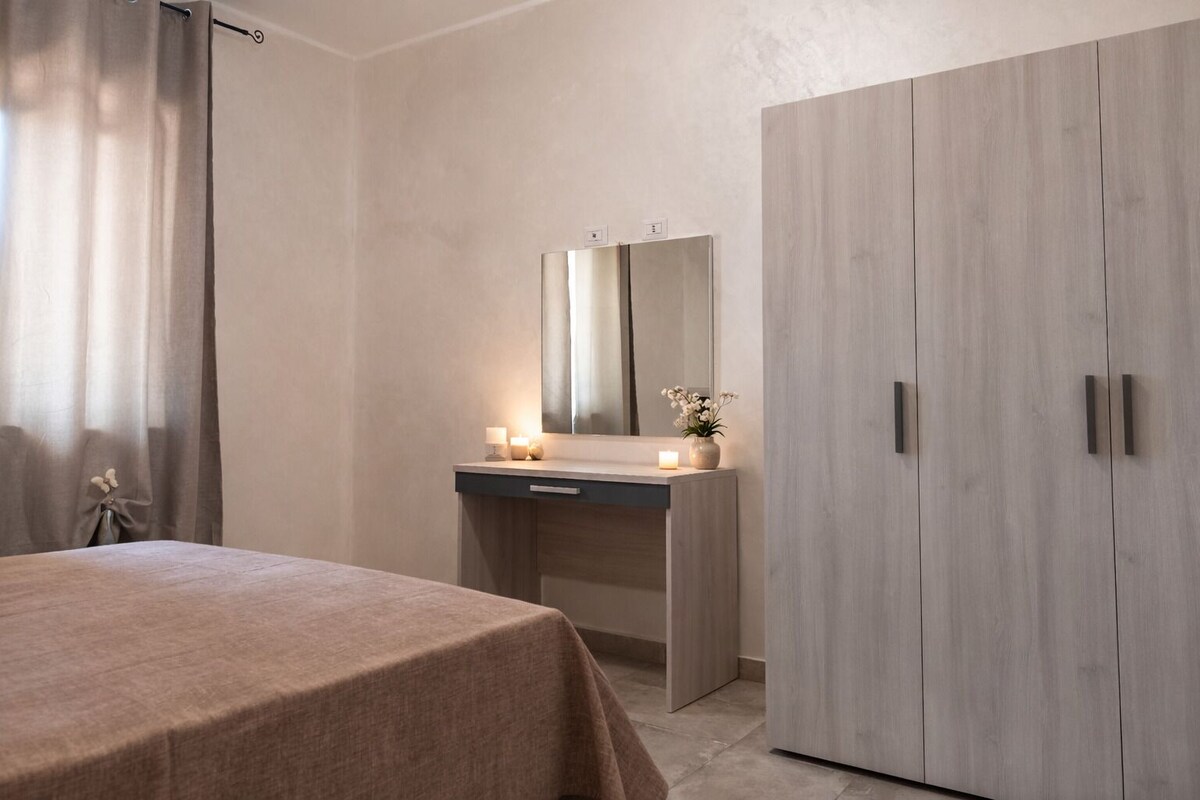 Une chambre à coucher comprenant un lit, une table de chevet avec un miroir, une commode et une armoire.