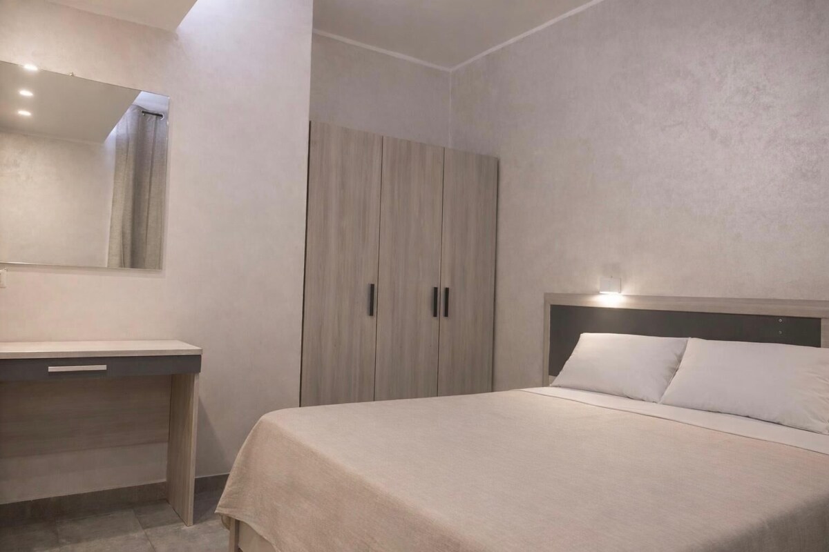 Une chambre à coucher comprenant un lit, une table de chevet, une armoire et un miroir.