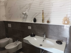 Une salle de bain moderne avec un lavabo blanc, un bidet et un porte-serviettes.