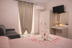 Une chambre d’hôtel comprenant un lit, un canapé, une armoire, une télévision et un miroir.