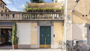 Un edificio con una puerta verde, un balcón con plantas y una bicicleta estacionada afuera.