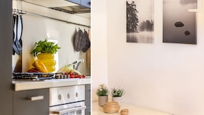 Una cocina con estufa, horno y diferentes utensilios. Hay plantas en macetas y un cuadro en la pared.