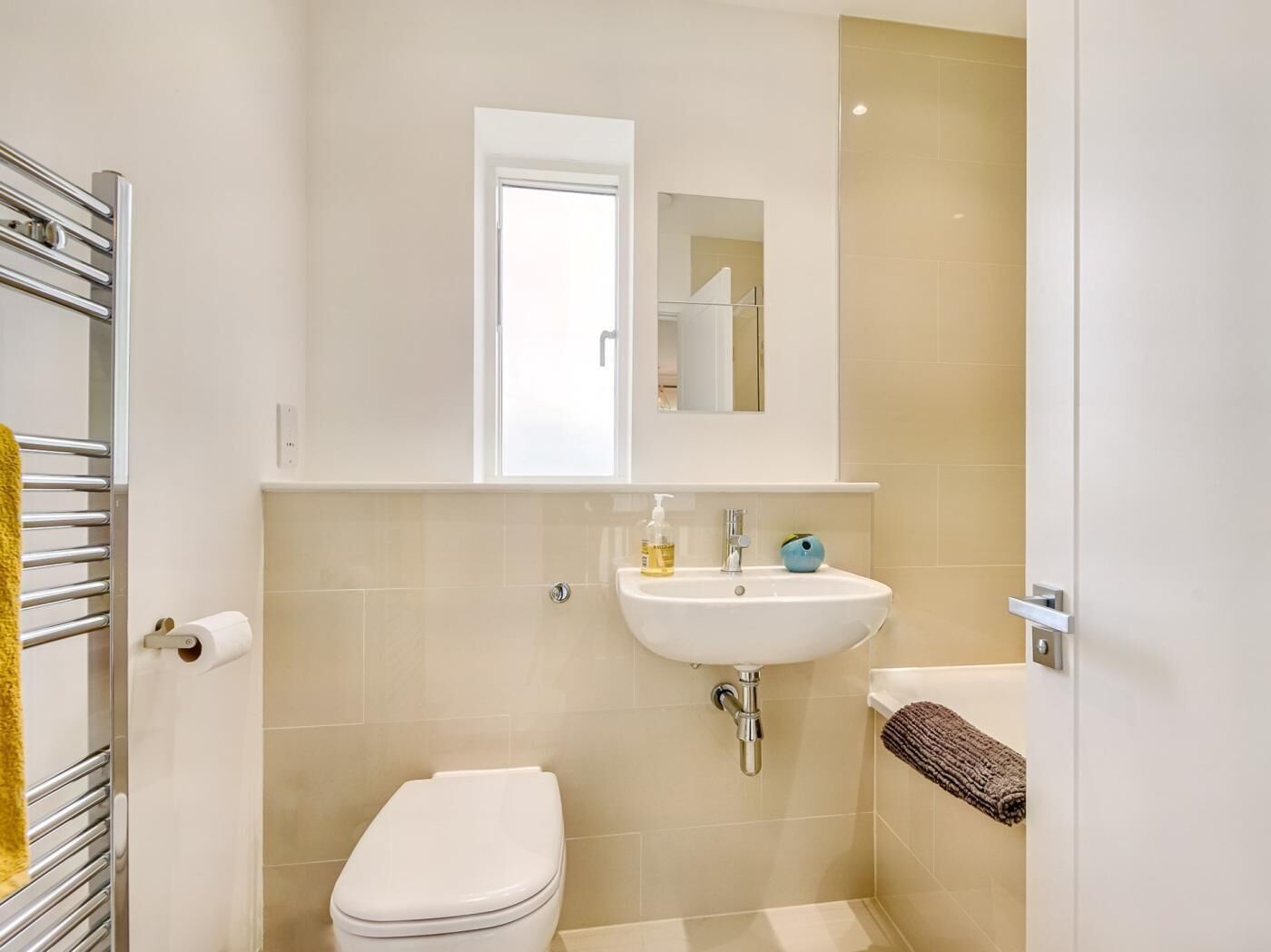 A bathroom with a toilet, sink, and towel rack.