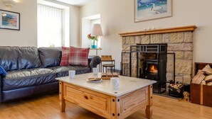 Un salon chaleureux avec une cheminée, un canapé en cuir, une table basse en bois et un tableau accroché au mur.