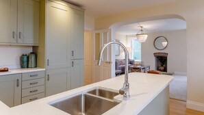 A kitchen with a central island, double sink, and light-colored cabinets. - 2 Bed in Bideford (oc-77589) (Northam)
