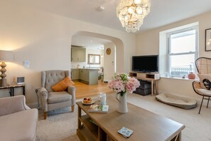Ein modernes Wohnzimmer mit Sofa, Couchtisch, Fernseher und einem Platz für ein Haustier.